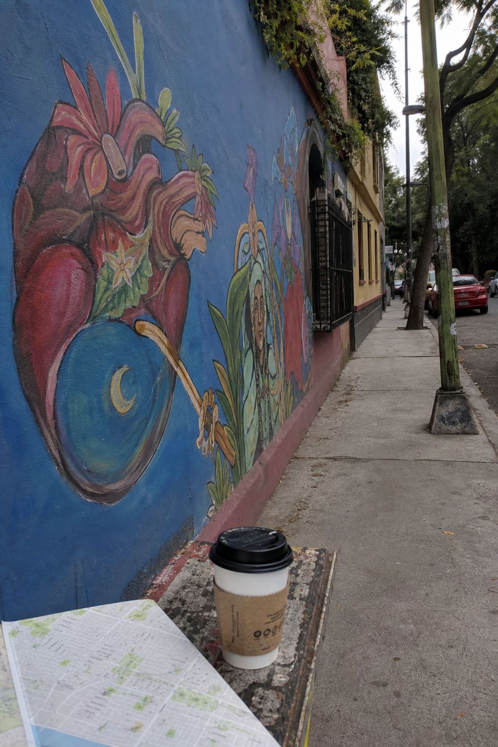 En la imagen hay un mural colorido en una pared. Hay una taza de café y un ma...