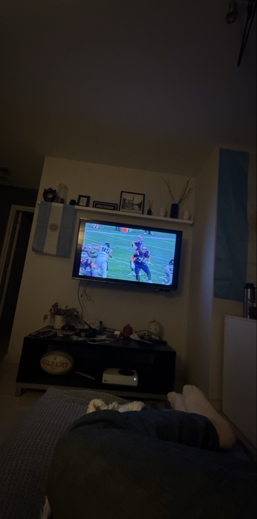 In the living room, there is a television showing a football match. There are...